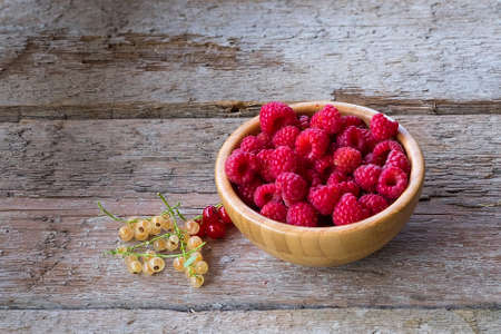 Organic raspberries in bowl on wood background.の写真素材