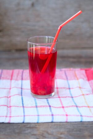 Glass of cherry juice or compote on wooden table with cherriesの写真素材