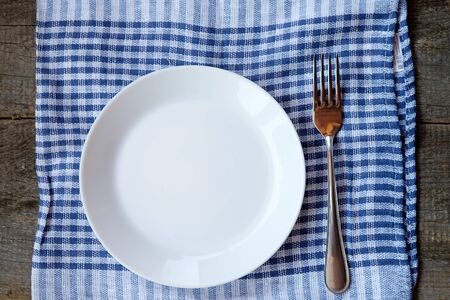 Empty plate, fortk and towel over wooden table background.の写真素材