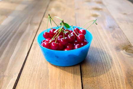 Sweet ripe cherries in the blue bowl on wood background.の写真素材