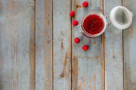 Open a jar of raspberry jam on the wooden table. Background layout with free text space.の写真素材