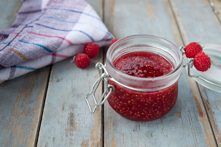 Open a jar of raspberry jam on the wooden table. Background layout with free text space.の写真素材