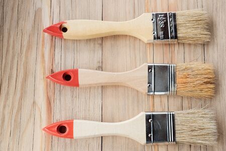Three paint brushes on a wooden table in the centerの写真素材