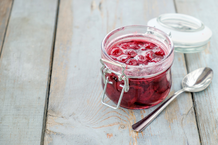 Jar of cherry jam and sppon. Rustic table backgroundの写真素材