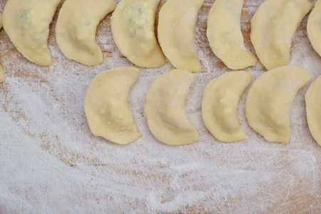 Vareniki dumplings or pelmeni before boiling on the wooden desk. Bakery Background. Rustic Styleの写真素材