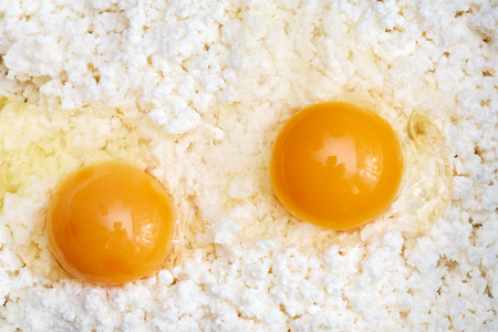 Cottage cheese and two eggs close-up background. Top Viewの写真素材