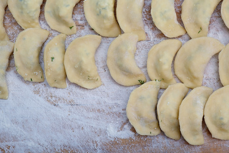 Vareniki dumplings or pelmeni before boiling on the wooden desk. Top view.の写真素材