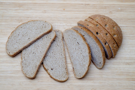 Sliced fresh brown bread on wooden board. Top Viewの写真素材