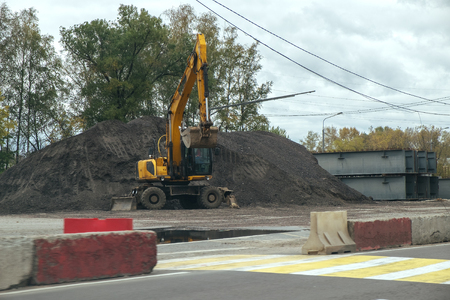 Yellow heavy excavator during construction of the new roadの写真素材