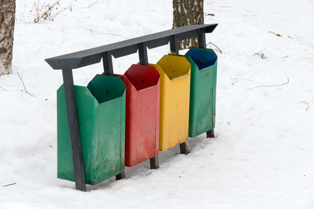 Colorful trash bins in the snow in winter park. Green, red and yellow trash boms.の写真素材