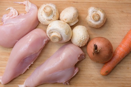 Fresh champignons, carrot, chicken fillet, and onion on wooden kitchen cutting board. Tp Viewの写真素材
