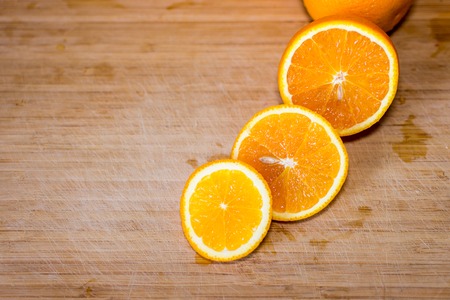 Sliced sweet orange and a steel knife on a wooden board. Empty space for your text