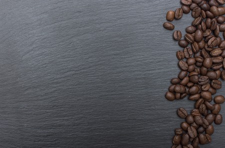 Coffee beans on black background of slate or stone background with copy space. Top view