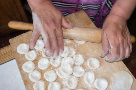 Rolling the dough with a rolling pin on the wooden desk. Close upの写真素材