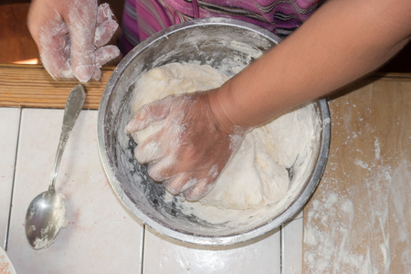 Close up view of baker kneading dough. Hands preparing dough in metal cup. Woman hands kneading...
