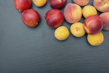 Ripe apricot and nectarine on black background of slate or stone.の写真素材