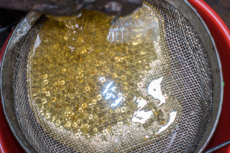 Strain the poured honey through a sieve. How to Harvest Honey. Filtering raw honey.の写真素材