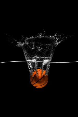 Basketball falls into the water on black backgroundの写真素材