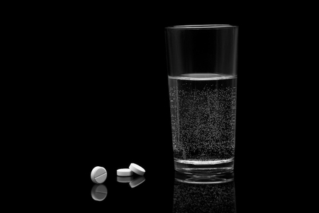 Glass with water and pills on a black backgroundの写真素材