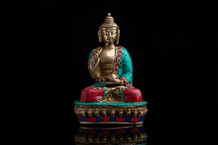A buddha figure made of metal on a black backgroundの写真素材