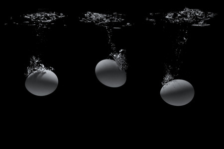 Eggs in water on a black backgroundの写真素材