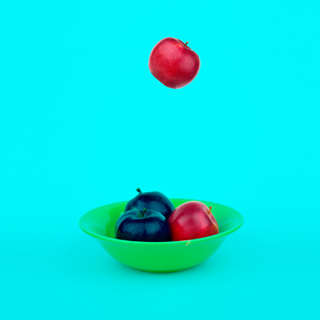 A red apple falls into a yellow plate. Art Still Life of Applesの写真素材