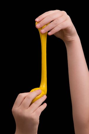 Yellow slime in the hands of a girl. Play with mucus.の写真素材