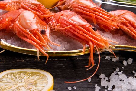 Shrimp, salt and lemon on a wooden background. Seafood.