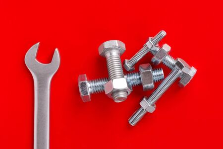 Wrench and bolts with nuts close-up on a red background.