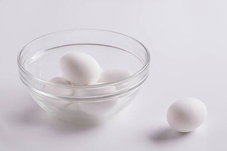White raw eggs in a glass plate on a white background.