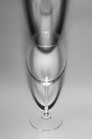 Empty wine glass. An empty glass of wine casting an unusual shadow.の写真素材