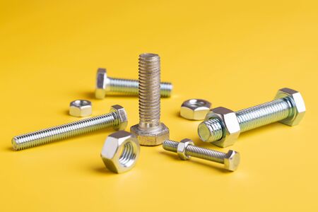 Bolts and nuts close-up on a yellow background.