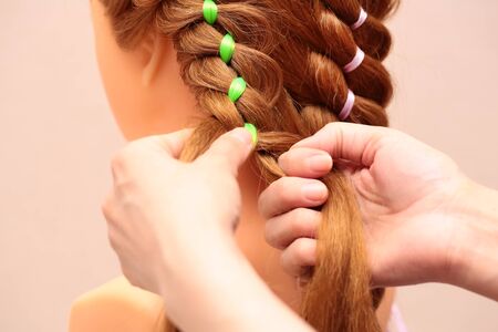 Weaving braids with colored ribbons.