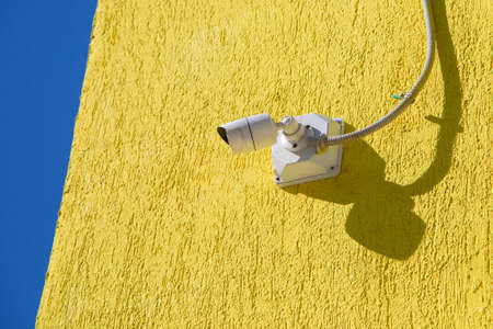 CCTV camera on a yellow wall.の写真素材