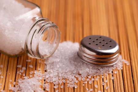 Scattered crystals of white salt from a salt cellar.