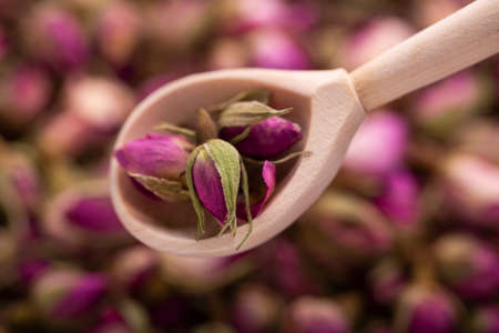 Dried rosebuds in a wooden spoon close-up.の写真素材