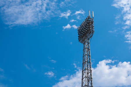 Large spotlights lighting the stadium against the blue sky.