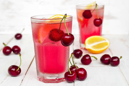 Lemonade with fresh cherries on white wooden backgroundの写真素材