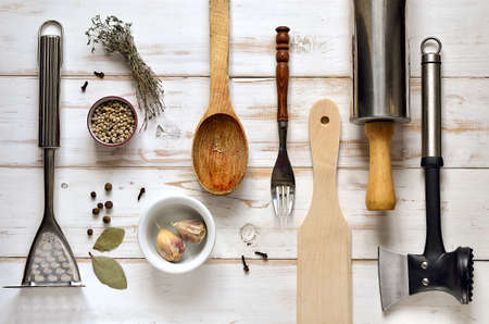 Kitchen utensils on a light rustic wooden background