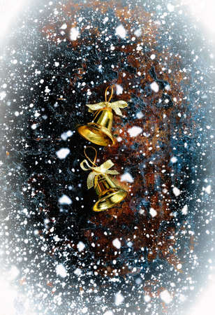 Christmas bells on a dark vintage background with snowfallの写真素材