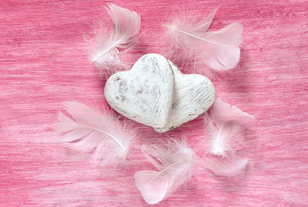 Valentines hearts on a pink background decorated with white featherの写真素材
