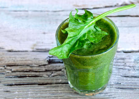 Green spinach smoothie in a glass with fresh leafの写真素材