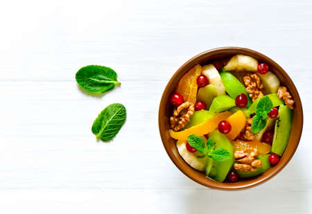 Fresh fruit and berries salad with walnuts and mint, vitamin booster for healthy breakfast, top viewの写真素材