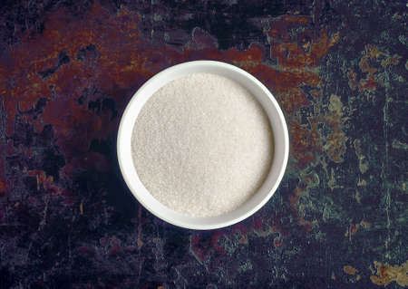 White round bowl with sugar in it on a vintage background, stylized image, can be used both horizontal and vertical, top viewの写真素材