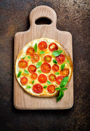 Traditional pizza on wooden board  on a dark vintage background, top viewの写真素材