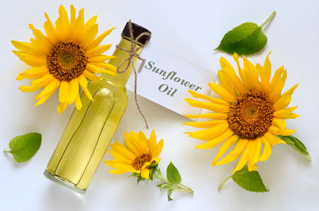 Sunflower oil in a glass bottle decorated with fresh sunflowers on a light background, top viewの写真素材