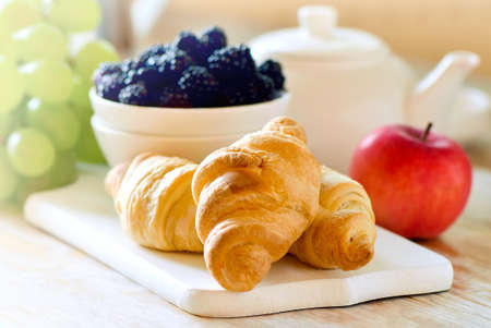 Rustic early morning breakfast with freshly baked croissants and various fruits berries and tea, stylized image, selective focusの写真素材