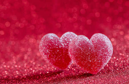 Marmalade hearts covered with sugar on a sparkling red backgroundの写真素材