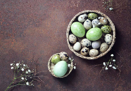 Spring painted green eggs in two baskets decorated with flower branches, view from above, Easter...