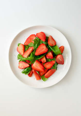 Spinach and strawberry salad with poppy seeds and vegetable oil dressing, healthy and refreshing vegetarian dish, top viewの写真素材